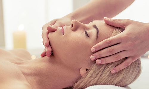 Eine Frau empfängt eine wohltuende Gesichtsmassage.
